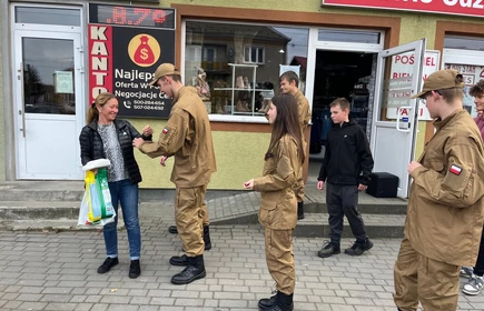 Na zdjęciu uczniowie klasy pożarniczej CKZiU w Łapanowie wraz mieszkańcami Łapanowa i okolic podczas akcji „Noś odblaski”. Fotografia barwna wykonana w centrum Łapanowa.