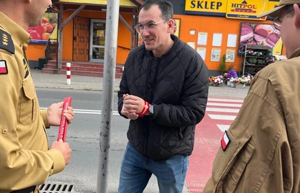 Na zdjęciu uczniowie klasy pożarniczej CKZiU w Łapanowie wraz mieszkańcami Łapanowa i okolic podczas akcji „Noś odblaski”. Fotografia barwna wykonana w centrum Łapanowa.