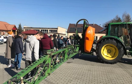 Na zdjęciu uczestnicy szkolenia z zakresu stosowania środków ochrony roślin przy ciągniku z opryskiwaczem podczas części praktycznej kursu. Zdjęcie wykonano na placu przy budynku "B" CKZiU w Łapanowie.   