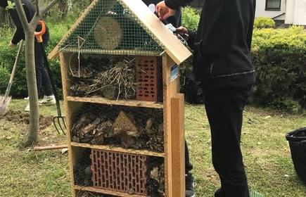Na zdjęciu uczniowie CKZiU w Łapanowie wypełniają domek dla owadów. Fotografia wykonana w szkolnym ogrodzie.