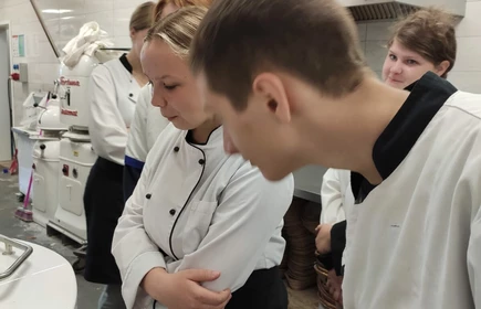 Zdjęcie przedstawia młodzież przyglądającą się pracy specjalistycznych urządzeń.