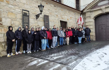 Grupowe zdjęcie młodzieży uczestniczącej w wycieczce,  wykonane przed budynkiem Zakładu Karnego w Nowym Wiśniczu.