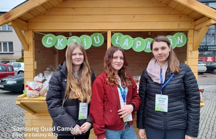 Na zdjęciu od lewej: Karolina Duda (kl. 2 TA), Katarzyna Mentel (kl. 2 TA) i Pani Kinga Fasuga na tle wielkanocnego stoiska CKZiU w Łapanowie.
