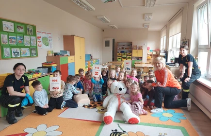 Na zdjęciu grupa przedszkolaków z Publicznego Przedszkola w Łapanowie wraz z panią Celiną Jacewicz oraz uczennicami: Wiktorią Klasło i Justyna Kącką. Zdjęcie wykonane w Publicznym Przedszkolu w Łapanowie podczas warsztatów udzielania pierwszej pomocy przedmedycznej.  