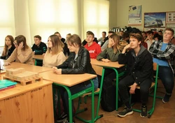 grupa osób siedzących przy biurkach w klasie