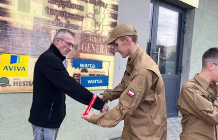 Na zdjęciu uczniowie klasy pożarniczej CKZiU w Łapanowie wraz mieszkańcami Łapanowa i okolic podczas akcji „Noś odblaski”. Fotografia barwna wykonana w centrum Łapanowa.