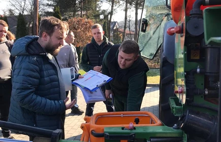 Na zdjęciu prowadzący i uczestnicy szkolenia z zakresu stosowania środków ochrony roślin przy ciągniku z opryskiwaczem podczas części praktycznej kursu. Zdjęcie wykonano na placu przy budynku "B" CKZiU w Łapanowie.   