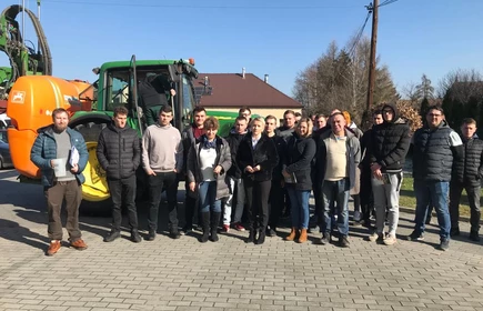 Na zdjęciu prowadzący i uczestnicy szkolenia na tle ciągnika z opryskiwaczem. Zdjęcie wykonano na placu przy budynku "B" CKZiU w Łapanowie.  