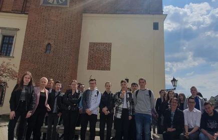 Fotografia barwna. Grupowe zdjęcie uczestników wycieczki przed Ratuszem w Tarnowie. 