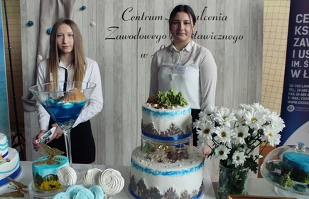 Na zdjęciu od lewej: Katarzyna Bzdyl i Wanda Malarczyk na tle stoiska gastronomiczno-cukierniczego promującego naszą szkołę.