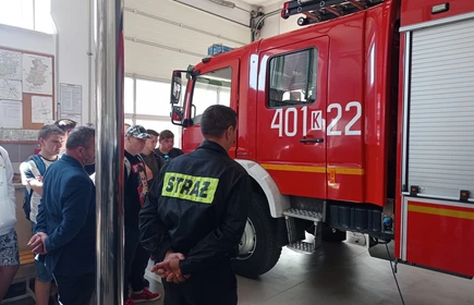 Zdjęcie młodzieży uczestniczącej w wycieczce, w tle wóz strażacki. 