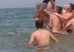 trzech chłopaków wrzucających kolegę do wody
