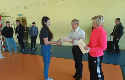 Na zdjęciu dyplom za zdobycie I miejsca w Mistrzostwach szkoły w tenisie stołowym odbiera Wanda Malarczyk, kl. 3 AP. Dyplom wręcza pani dyrektor - mgr inż. Dorota Matlęga oraz pani Celina Jacewicz. Zdjęcie wykonane w Hali Sportowej CKZiU w Łapanowie.  
