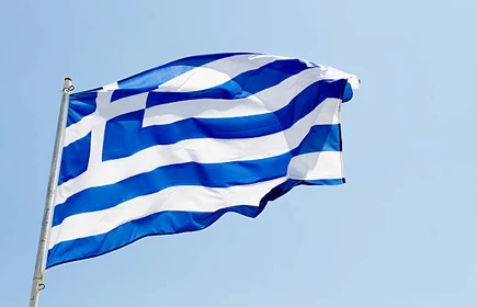 Flaga Grecji powiewająca na tle błękitnego nieba