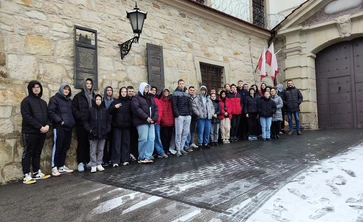 Grupowe zdjęcie młodzieży uczestniczącej w wycieczce,  wykonane przed budynkiem Zakładu Karnego w Nowym Wiśniczu.