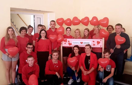 Fotografia barwna: grupowe zdjęcie uczestników Akcji &#34;Czytamy z Sercem&#34;, wykonane w Hali Sportowej CKZiU w Łapanowie.