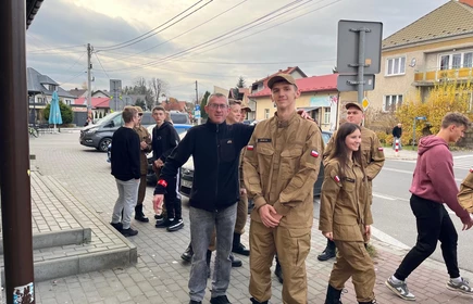 Na zdjęciu uczniowie klasy pożarniczej CKZiU w Łapanowie wraz mieszkańcami Łapanowa i okolic podczas akcji „Noś odblaski”. Fotografia barwna wykonana w centrum Łapanowa.