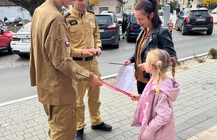 Na zdjęciu uczniowie klasy pożarniczej CKZiU w Łapanowie wraz mieszkańcami Łapanowa i okolic podczas akcji „Noś odblaski”. Fotografia barwna wykonana w centrum Łapanowa.