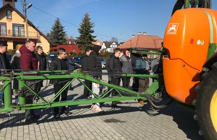 Na zdjęciu uczestnicy szkolenia z zakresu stosowania środków ochrony roślin przy ciągniku z opryskiwaczem podczas części praktycznej kursu. Zdjęcie wykonano na placu przy budynku "B" CKZiU w Łapanowie.   